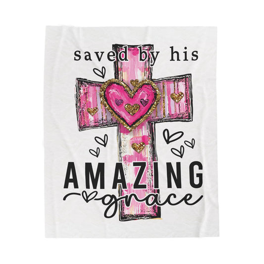 A blanket with a graphic design featuring a cross with a pink heart and the text 'saved by his AMAZING grace'